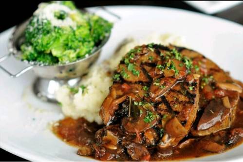 A plate featuring grilled meat with a savory sauce, mashed potatoes, and a side of steamed broccoli.