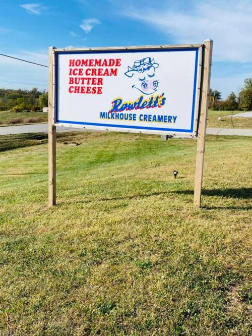 Sign for Rawlett's Milkhouse Creamery featuring homemade ice cream, butter, and cheese, set against a clear blue sky.