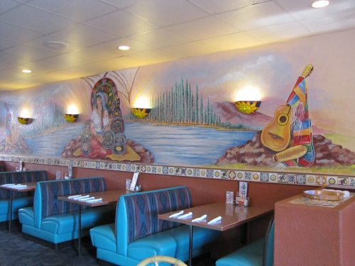 Colorful mural depicting nature and musical elements in a cozy restaurant setting with teal booths and tables.