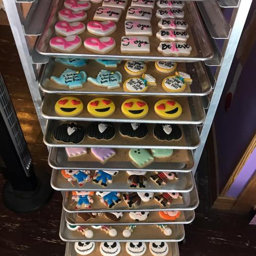 A metal rack filled with colorful decorated cookies, featuring various designs like hearts, emojis, and themed characters.
