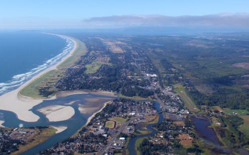 Aerial view of a coastal landscape featuring a beach, river, and lush greenery along the shoreline.