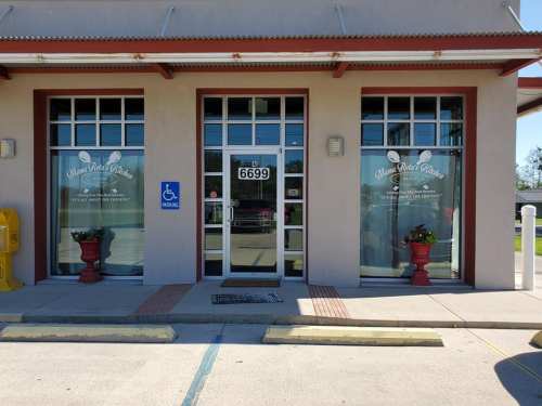Exterior of a restaurant with large windows, a door marked "6699," and planters on either side. Accessible parking available.