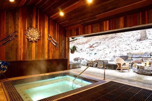 Cozy indoor hot tub with wooden walls, a sun decoration, and a view of a snowy outdoor area.