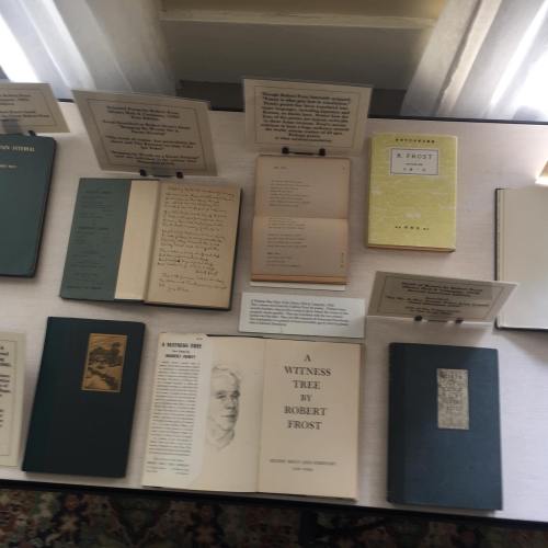 A display of books and manuscripts by Robert Frost, featuring various editions and accompanying informational plaques.