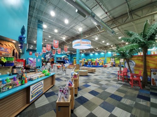 Brightly colored indoor play area with games, snacks, and a tropical theme, featuring palm trees and vibrant decor.