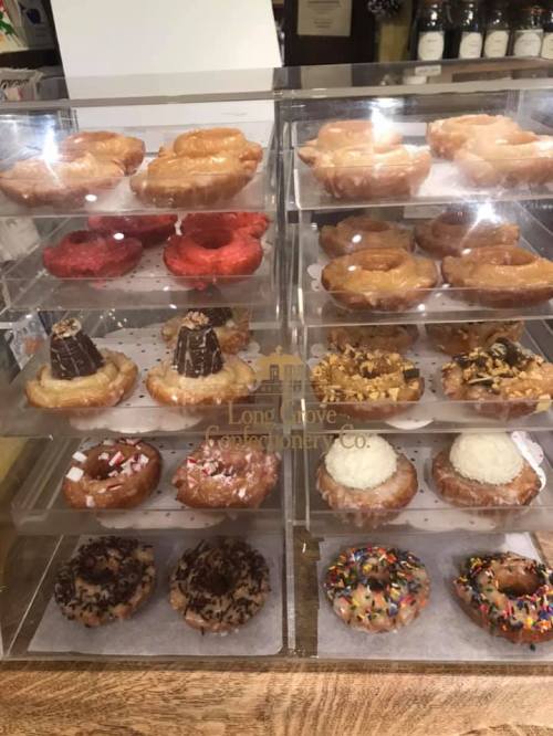 A display case filled with various donuts, including glazed, chocolate, and colorful sprinkles, arranged in tiers.