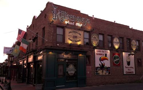 Exterior of Kilkenny's Irish Pub at dusk, featuring brick walls, neon signs, and Irish-themed decorations.