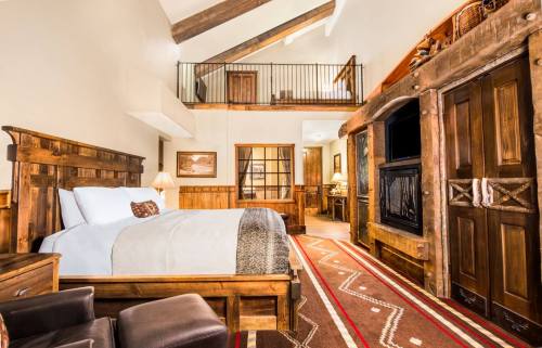 Cozy rustic bedroom with wooden furniture, a large bed, and a warm color palette, featuring high ceilings and a patterned rug.