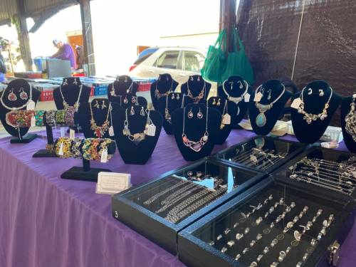 A display of various jewelry pieces, including necklaces, earrings, and bracelets, on black stands and a purple tablecloth.