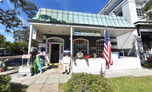 A colorful toy store with a sloth statue outside, featuring an American flag and various decorations.