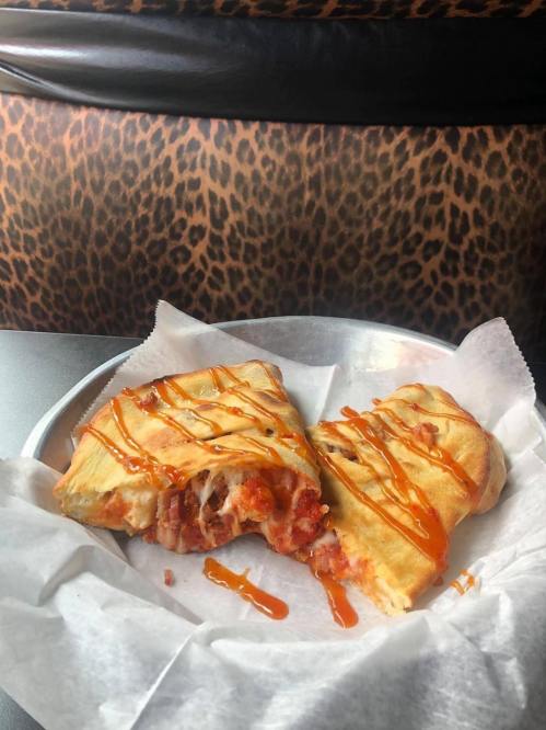 A plate with two pieces of stuffed pastry drizzled with sauce, set against a leopard print background.