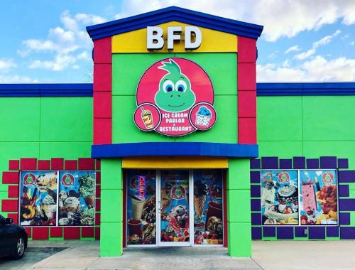 Colorful ice cream parlor exterior with a large sign, featuring playful graphics and vibrant wall colors.