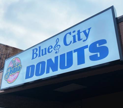 Sign for "Blue City Donuts" featuring a colorful donut graphic and musical note design.