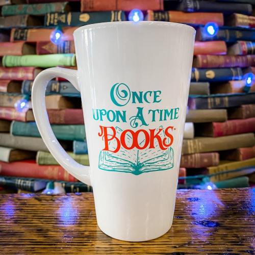 A white mug with the text "Once Upon a Time Books" and an open book illustration, set against a backdrop of stacked books.