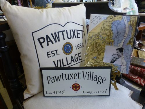 A decorative pillow and signs featuring "Pawtuxet Village," with a map and a black-and-white photo in the background.