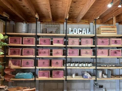 Shelves filled with wooden boxes and bottles, featuring a "LOCAL" sign above in a rustic setting.