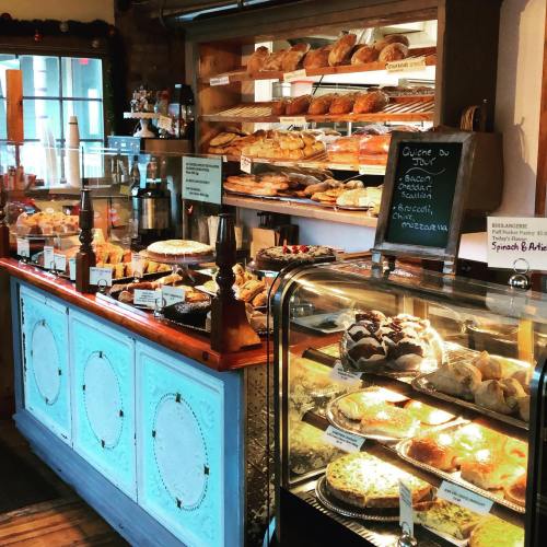 A cozy bakery display featuring a variety of pastries, breads, and desserts in a warm, inviting setting.