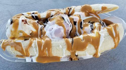 A banana split topped with scoops of ice cream, chocolate syrup, and drizzled peanut butter.