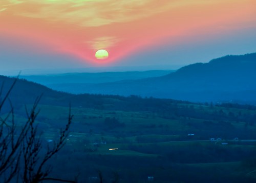 A serene sunset over rolling hills, with vibrant pink and orange hues illuminating the sky.