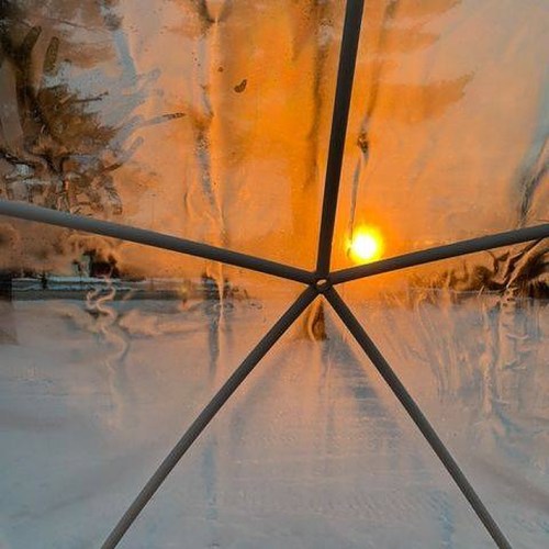 A sunset viewed through a foggy window, with warm orange hues and a snowy landscape outside.