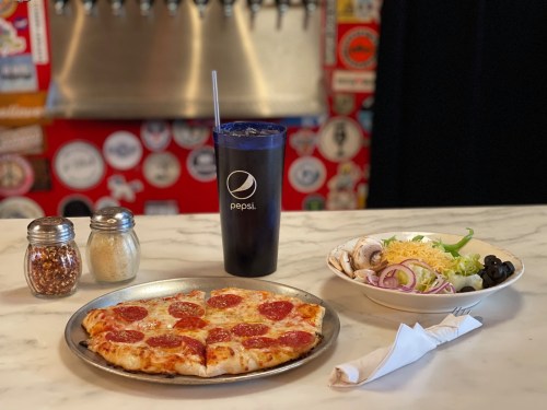 A plate of pepperoni pizza, a salad with toppings, and a Pepsi cup on a marble table with a colorful background.