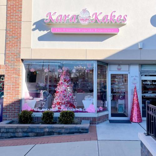 Exterior of Kara Kakes bakery featuring a pink-themed storefront and festive decorations, including a pink Christmas tree.
