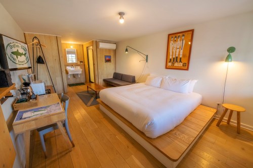 Cozy hotel room featuring a large bed, seating area, desk, and modern bathroom with wooden accents.