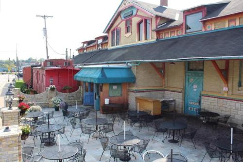 Outdoor seating area of a colorful restaurant with tables and chairs, surrounded by flowers and a historic building.
