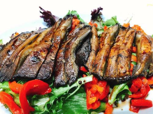 Grilled fish fillets served on a bed of mixed greens and red bell peppers.