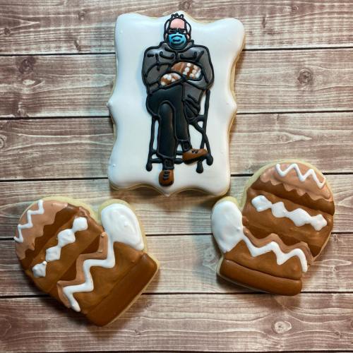 Decorative cookies featuring a seated figure in a mask and two mitten-shaped cookies on a wooden background.