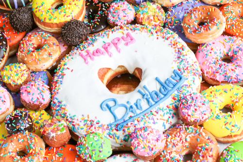 A colorful assortment of donuts, featuring a large birthday donut with "Happy Birthday" written on it.