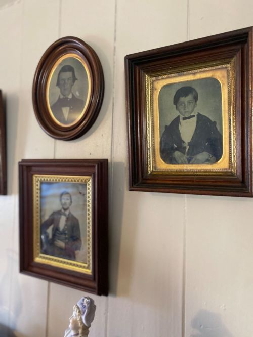 Three vintage framed portraits of boys in formal attire hanging on a wooden wall.