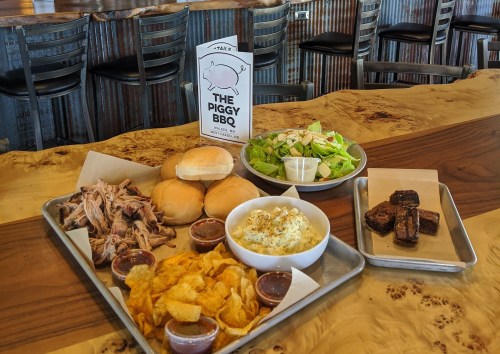 A tray of BBQ pulled pork, buns, chips, mac and cheese, salad, and brownies at The Piggy BBQ restaurant.