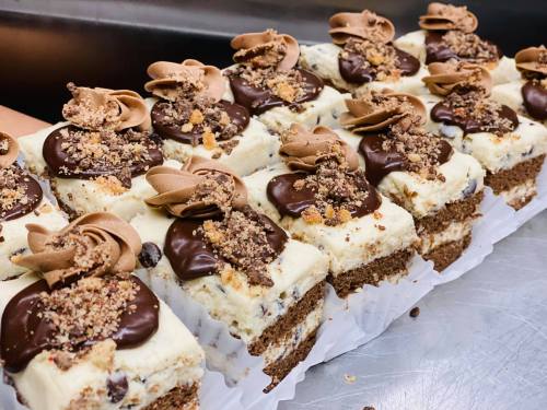 Delicious dessert bars topped with chocolate, cream, and crushed cookies, arranged neatly on a tray.