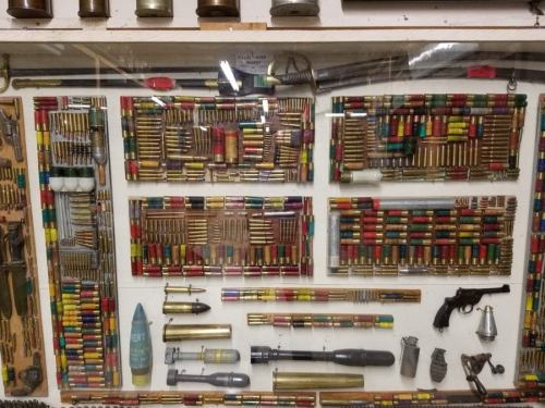 A display case filled with various colorful ammunition, shells, and military artifacts arranged artistically.