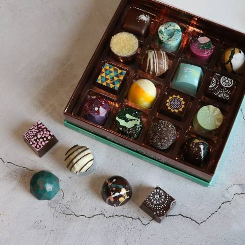 A colorful assortment of gourmet chocolates in a box, featuring various shapes and intricate designs.