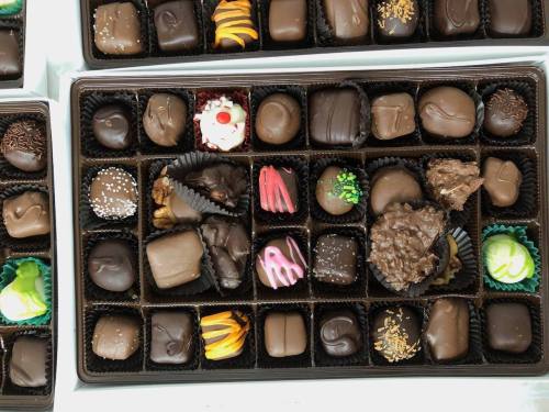 A variety of assorted chocolates in a box, featuring different shapes, colors, and toppings.