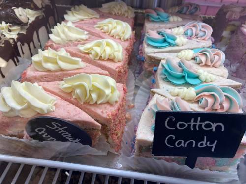 A display of colorful cake slices with frosting, labeled "Strawberry Crunch" and "Cotton Candy."