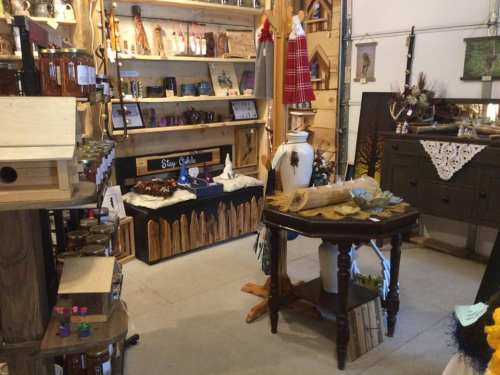 A cozy shop interior featuring wooden shelves, handmade crafts, and rustic decor items on display.