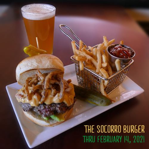 A delicious burger topped with cheese and crispy onions, served with fries and a drink, featuring a festive graphic.