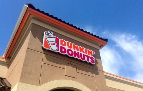 Sign for Dunkin' Donuts on a building against a clear blue sky.