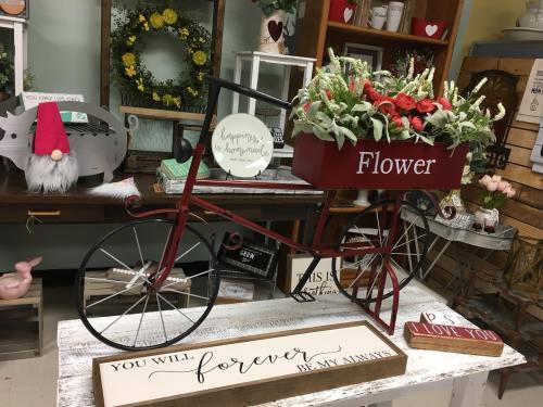 A decorative red bicycle planter with flowers, accompanied by a wooden sign that reads "You will forever be my always."