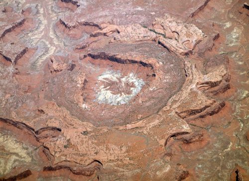 Aerial view of a circular rock formation surrounded by rugged terrain, showcasing earthy tones and textures.