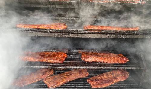 Smoky barbecue ribs cooking on a grill, with steam rising and a rich, smoky flavor evident.
