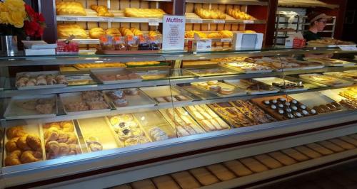 A display case filled with various baked goods, including muffins, pastries, and breads, in a bakery setting.