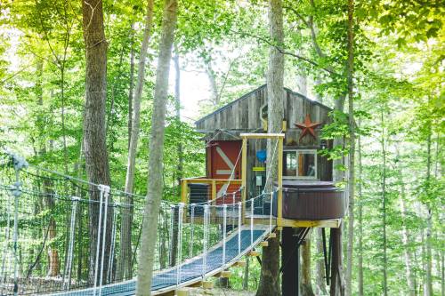 A charming treehouse with a wooden exterior and a rope bridge, nestled among lush green trees.