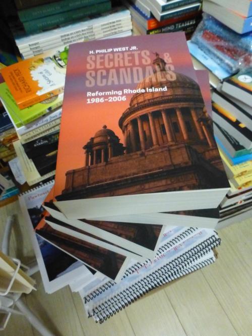 A stack of books with a prominent one titled "Secrets & Scandals" featuring a dome building on the cover.