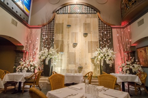 Elegant restaurant interior featuring a stone water wall, floral arrangements, and softly lit ambiance.