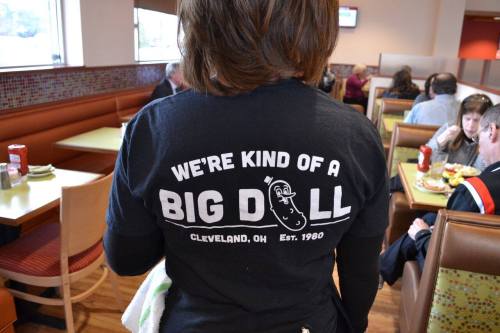 A person wearing a black t-shirt with the text "We're kind of a big dill" in a restaurant setting.