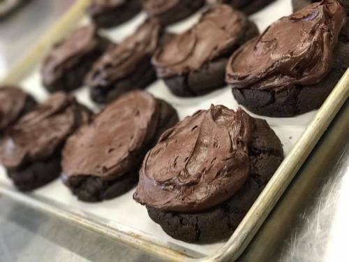 A tray of freshly baked chocolate cookies topped with rich chocolate frosting.